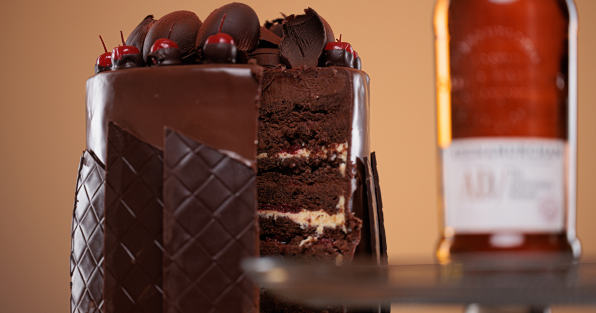 a Black Forest Cake with a bottle of whisky in the background