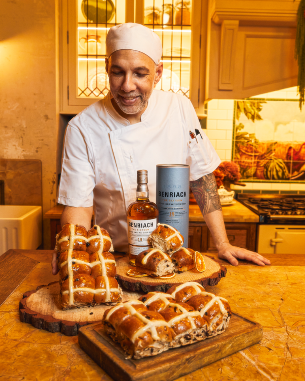 A baker next to some hot crodd buns and some whisky