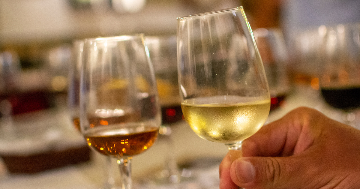 A hand holding a glass of fortified wine