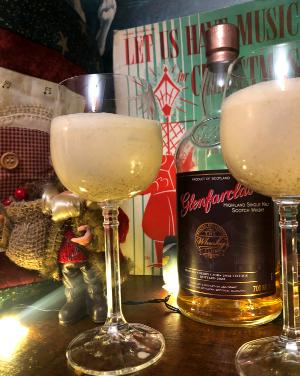 A glass of eggnog surrounded by whisky bottles